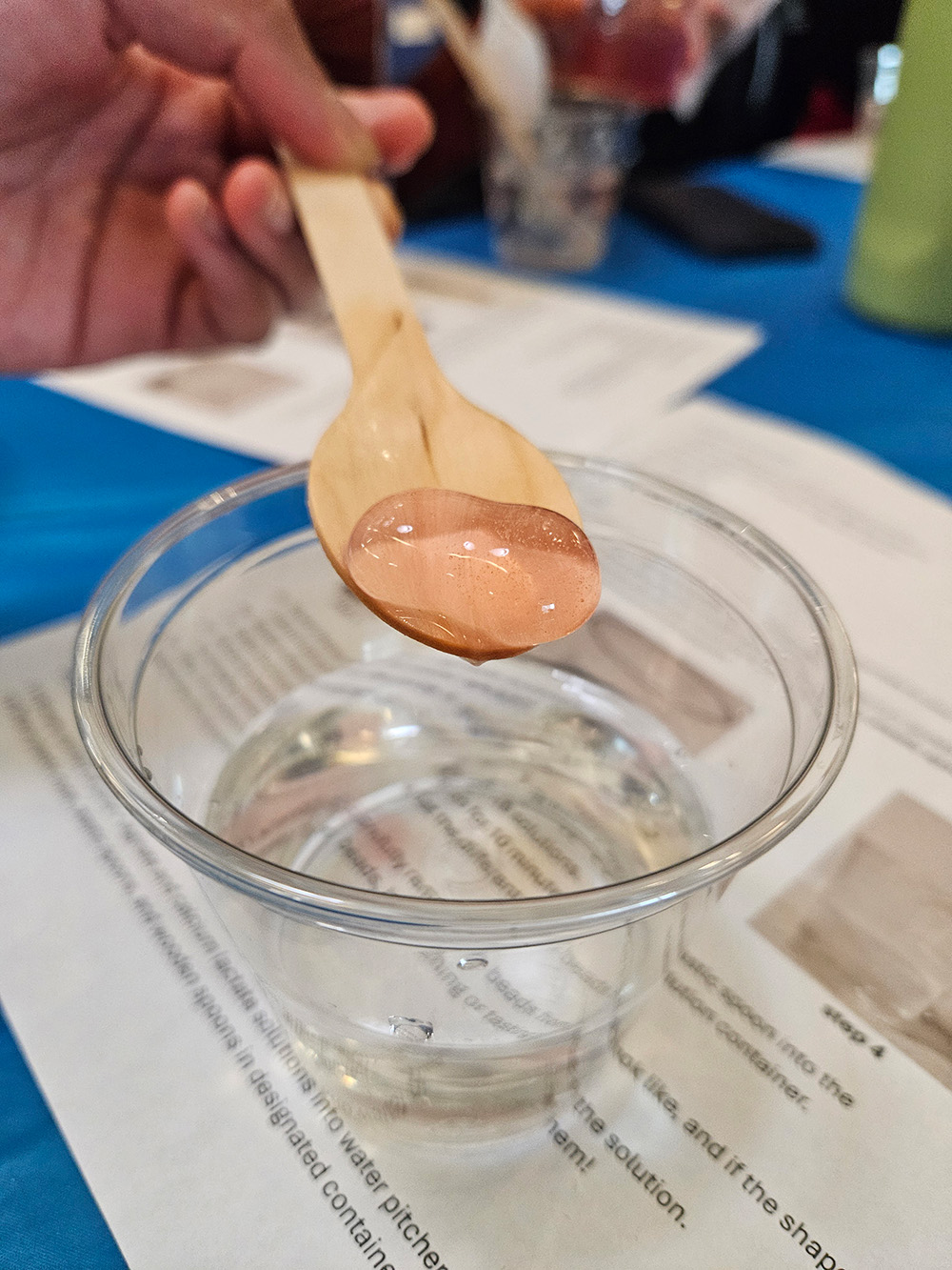 A capsule of hydrogel from a chemistry demo, on a spoon held by someone out of frame.