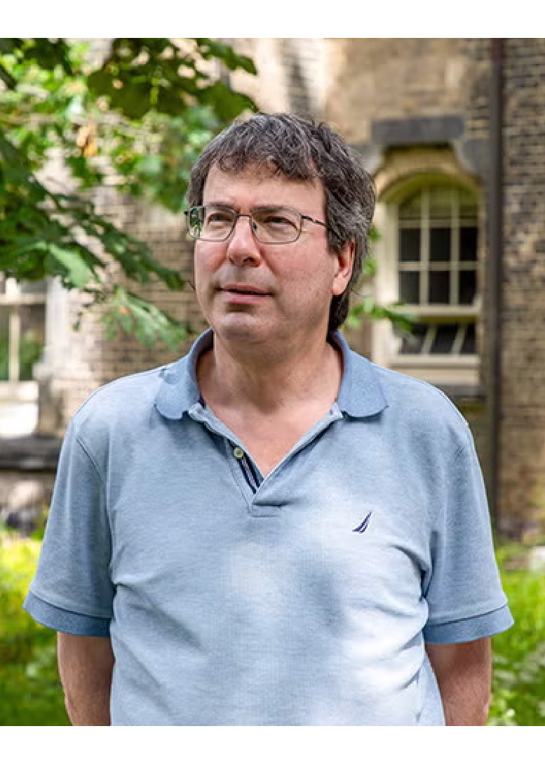 Portrait of Dr. Lewis Kay standing in front of a brick building.