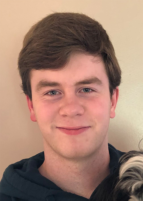 Head shot of a young white man with brown hair smiling into the camera.