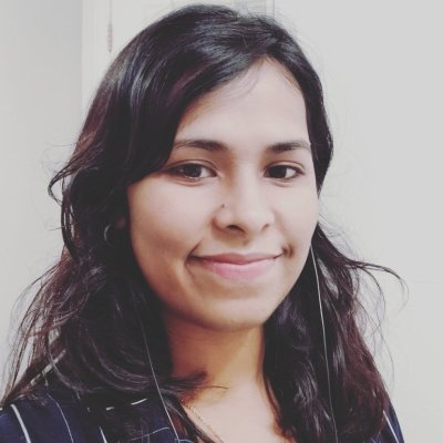 Head shot of a South Asian woman with shoulder-length black hair smiles in three-quarters profile.