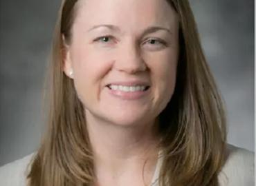 Head shot of a white woman with long, light-brown hair smiling into the camera.