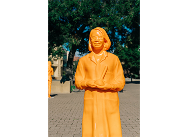 An orange statue of a woman with glasses