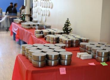 A series of stainless steel meal tins grouped on a table around a small holiday tree.
